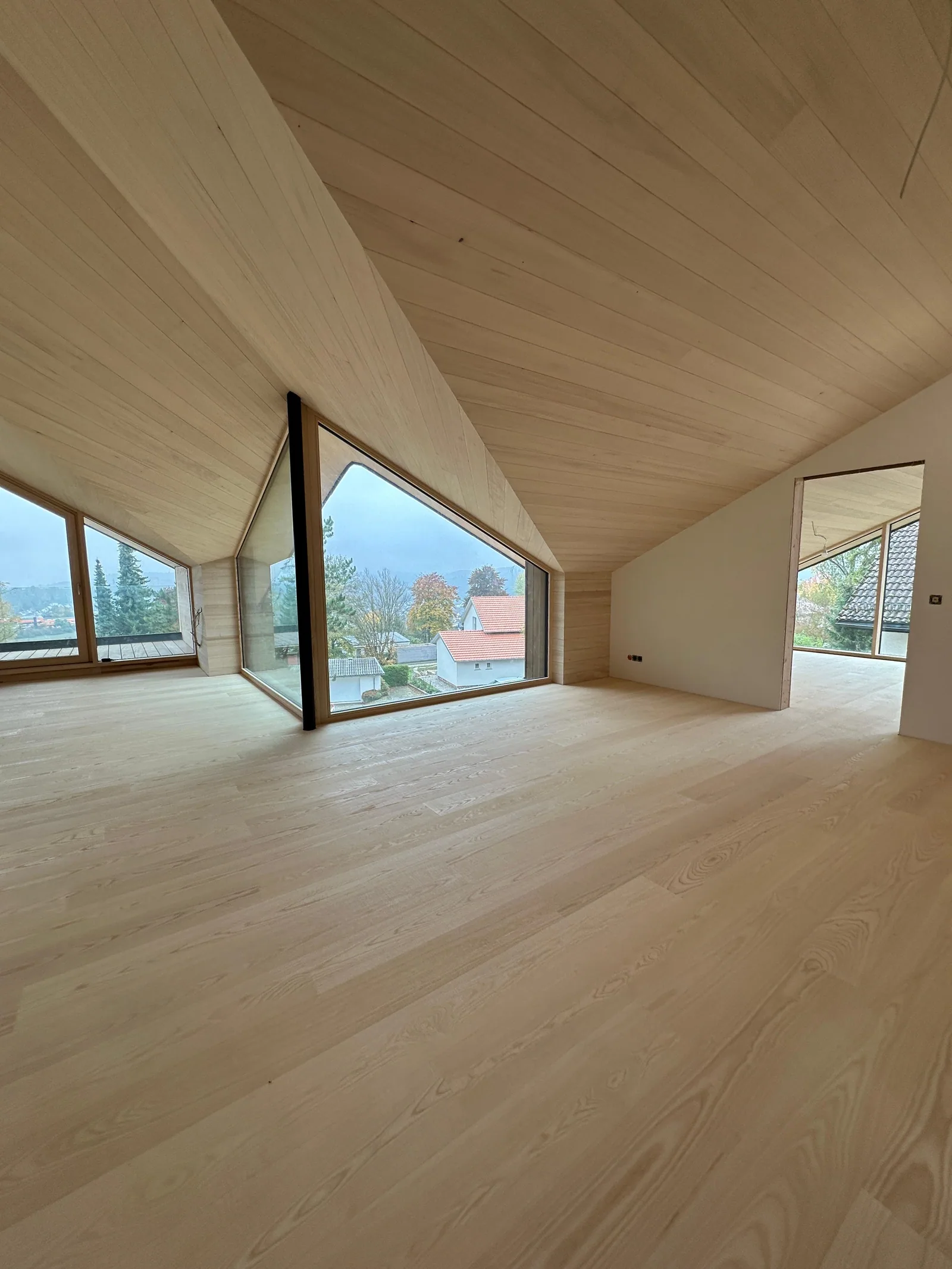 Heller Wohnraum mit präzise verlegtem Holzboden und großen Panoramafenstern